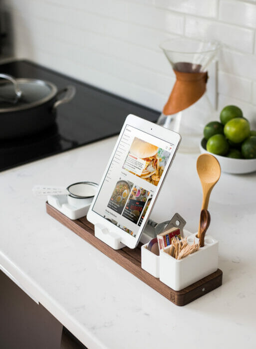 image shows kitchen scene with a tablet propped up with various kitchen utensils