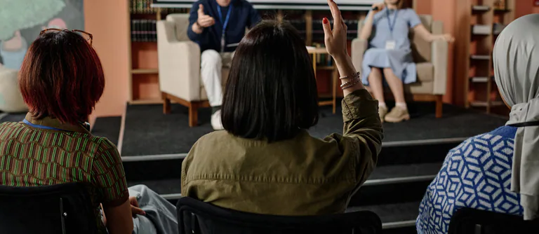 Unrecognizable Woman Raising Hand During Conference